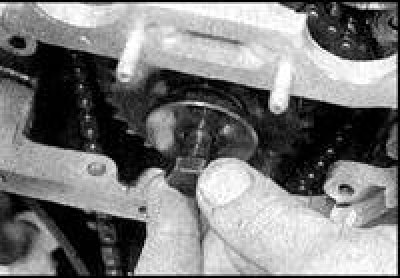 11. Отверните болт оси натяжителя нижней цепи и снимите башмак.