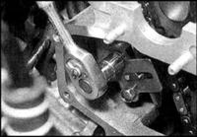 13. Установите башмак натяжителя нижней цепи и затяните болт оси башмака с заданным моментом.