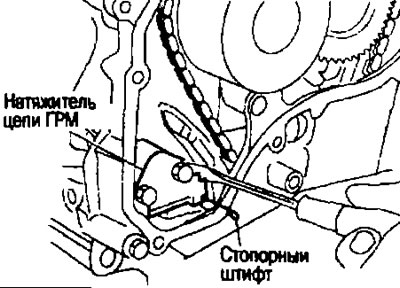 b. Вдавите плунжер натяжителя цепи. Вставьте стопорный штифт в отверстие в корпусе натяжителя,…